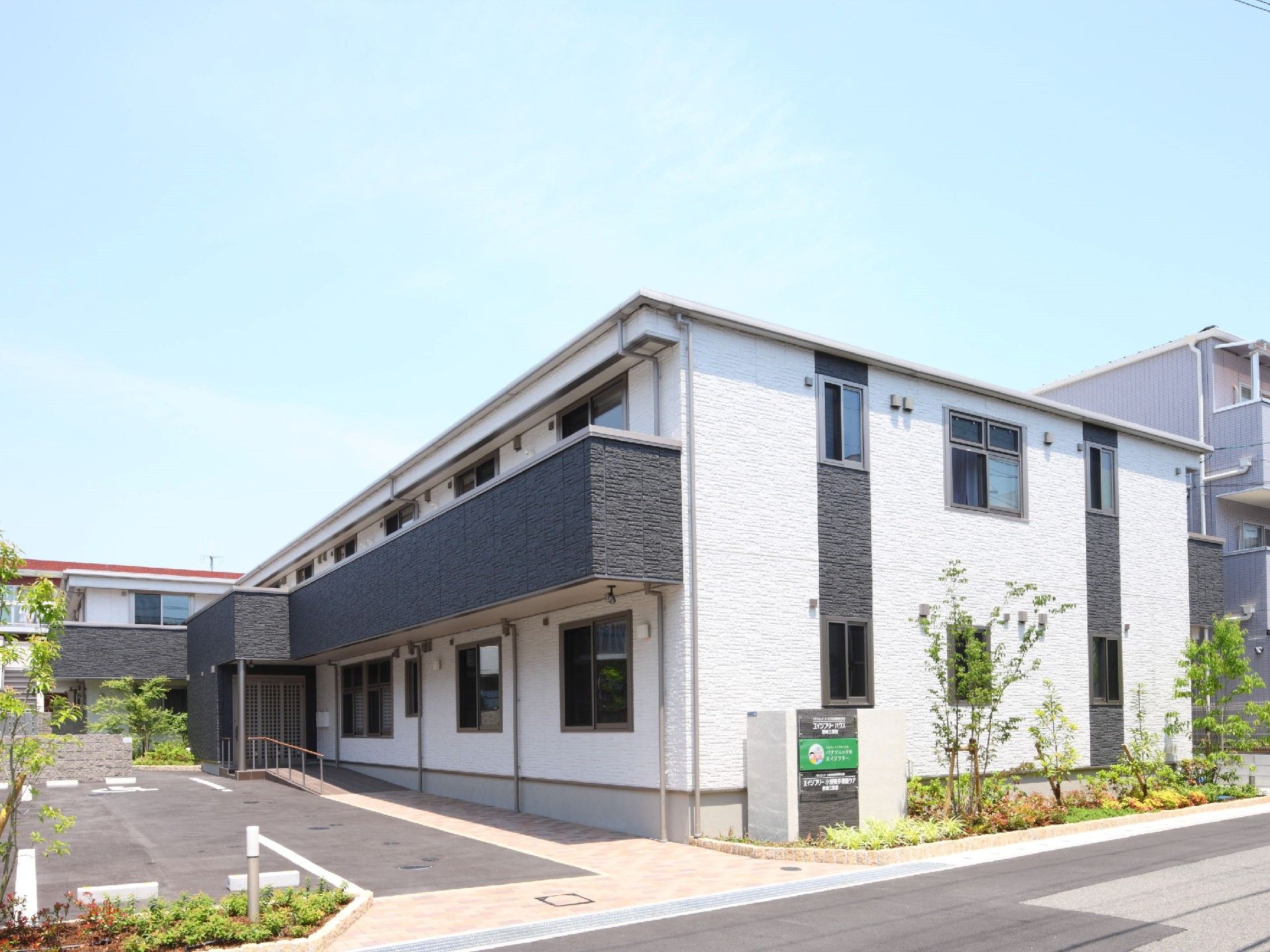 駐車場が付いた広い敷地内に2階建ての建物があり、2階部分にはベランダも付いている。