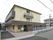 3階建ての建物にはベランダや駐車場が付き、玄関の周りには看板も立っている。