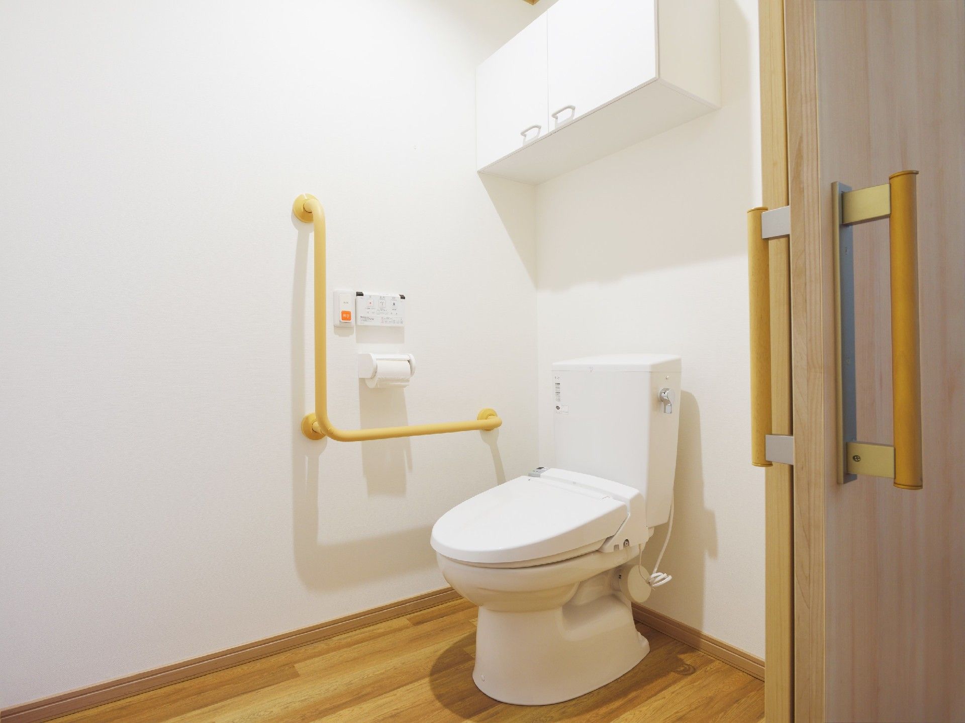 トイレは引き戸で広く、トイレットペーパーホルダーの横にはエル字型の手すりが設置されている。
