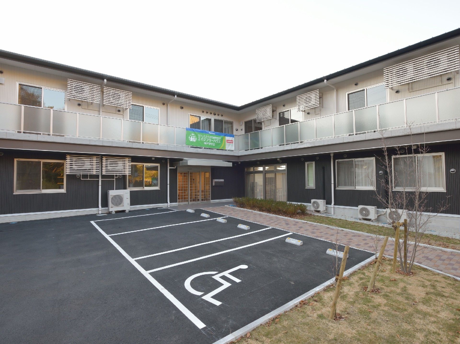 広い駐車場には車いすマークがつき、2階建ての建物にはベランダも付いている。