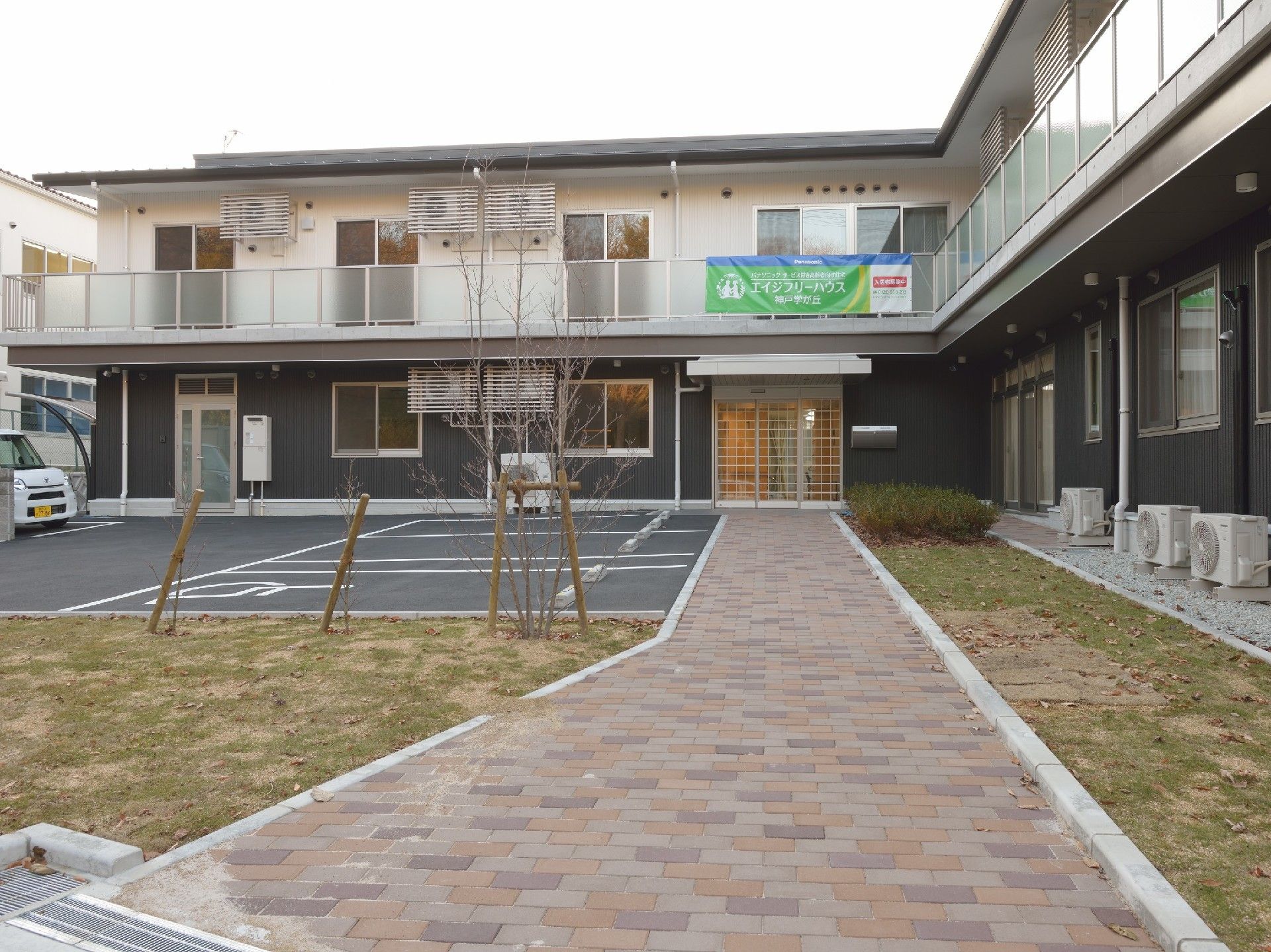 玄関には屋根が付き、レンガ調のブロックが敷かれたアプローチが続いている。