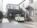 ２階建ての住宅があり、その前に車が１台停められている。玄関までは手すりの付いたスロープが設けられている。