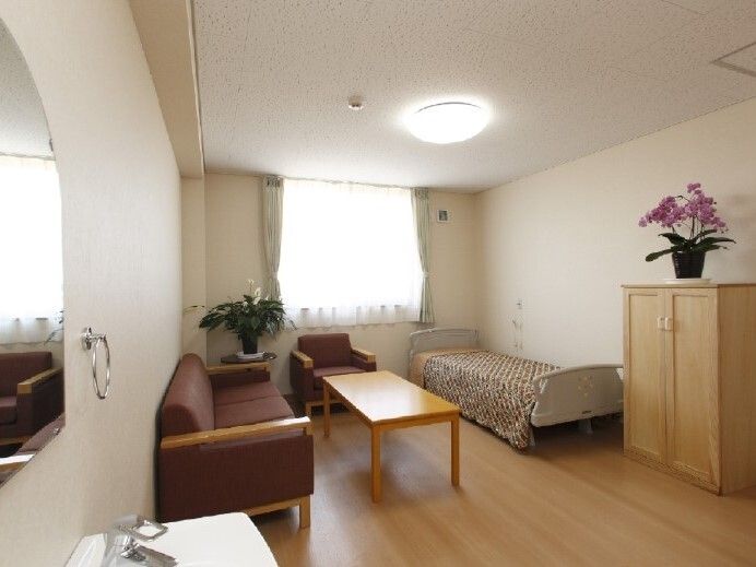 大きな窓が付いたフローリングの部屋には寝具付きのベッド屋収納家具、ソファなどが置かれている。