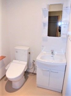 トイレの横には収納や鏡が付いた洗面所があり、白ですっきりとまとめられている。