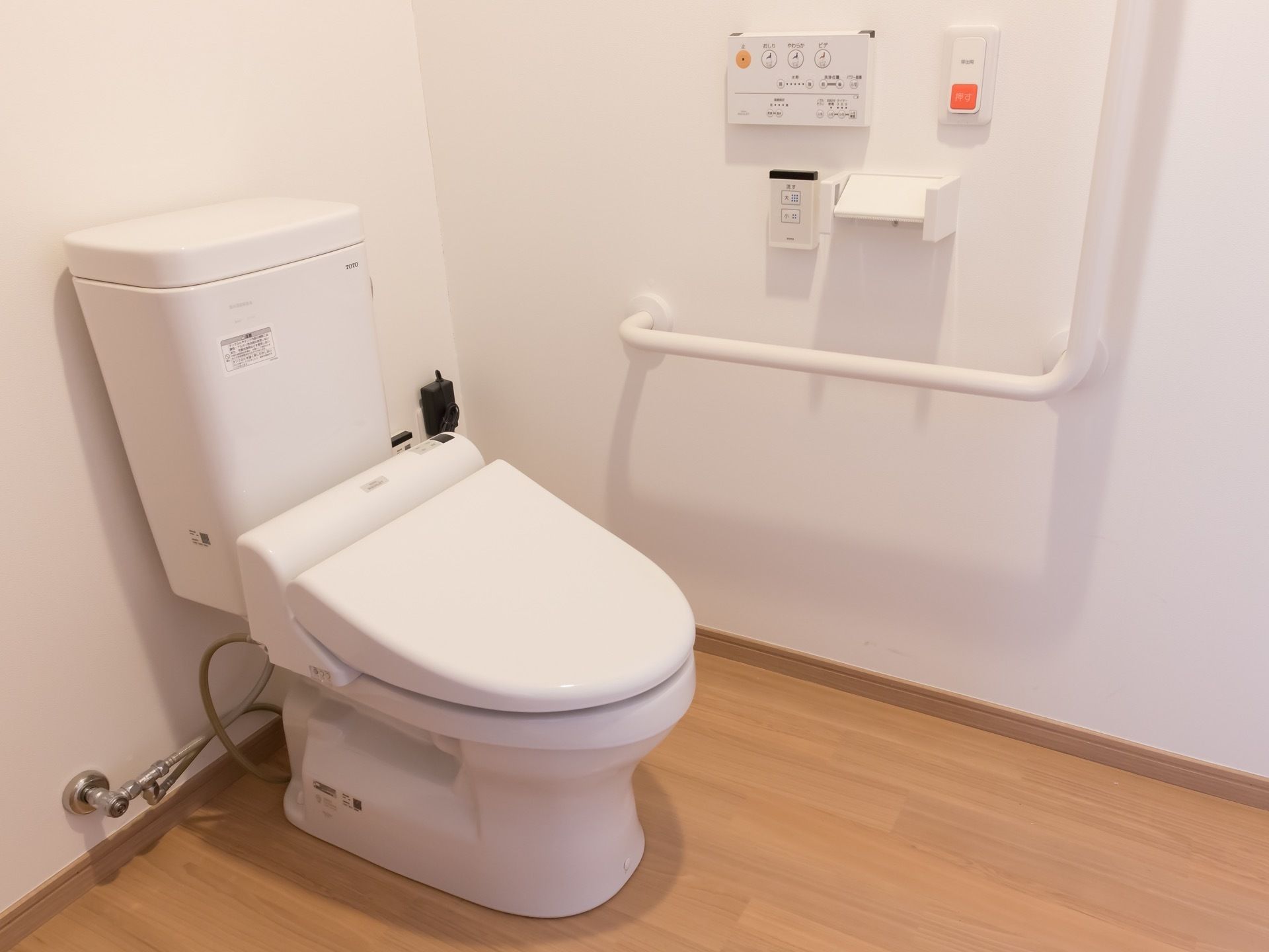 温水洗浄機能付きのトイレがある。壁にはＬ字型の手すりがあり、近くにはナースコールのボタンも付いている。