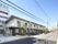 2階建ての建物。1階部分はブラウン、2階部分は白で、側面には屋外階段もある。