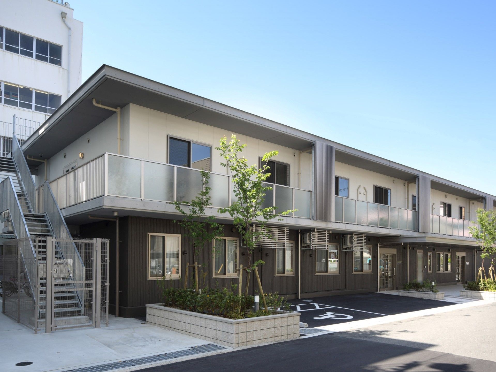 2階建ての建物は横に長く、1階部分はブラウン、2階部分は白で、側面には屋外階段もある。