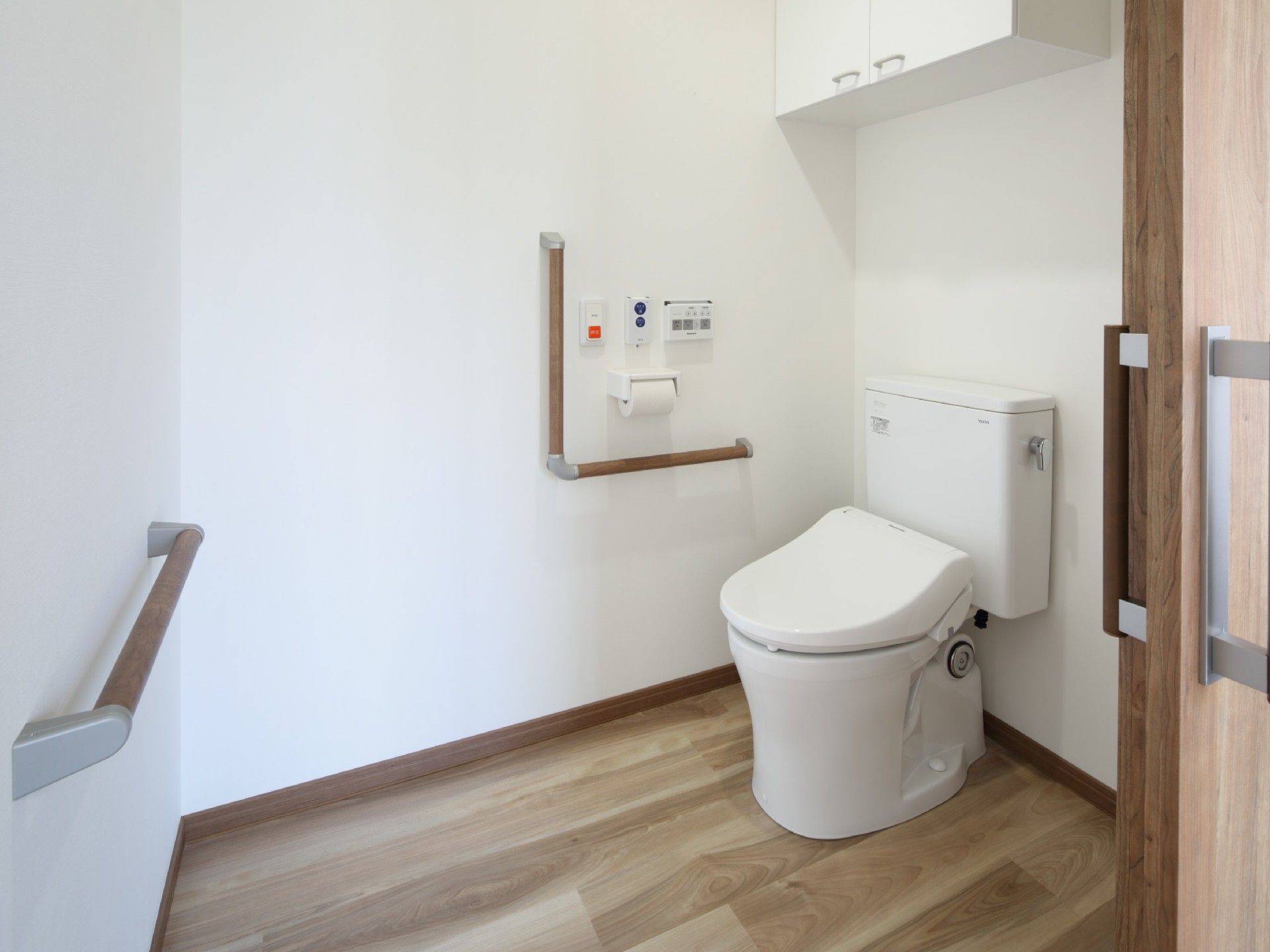 トイレは広く、手洗い場や手すりが付き、収納用の白い棚も設置されている。