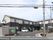 2階建ての建物。1階部分はダークグレー、2階部分は白で、側面には駐車場もある。