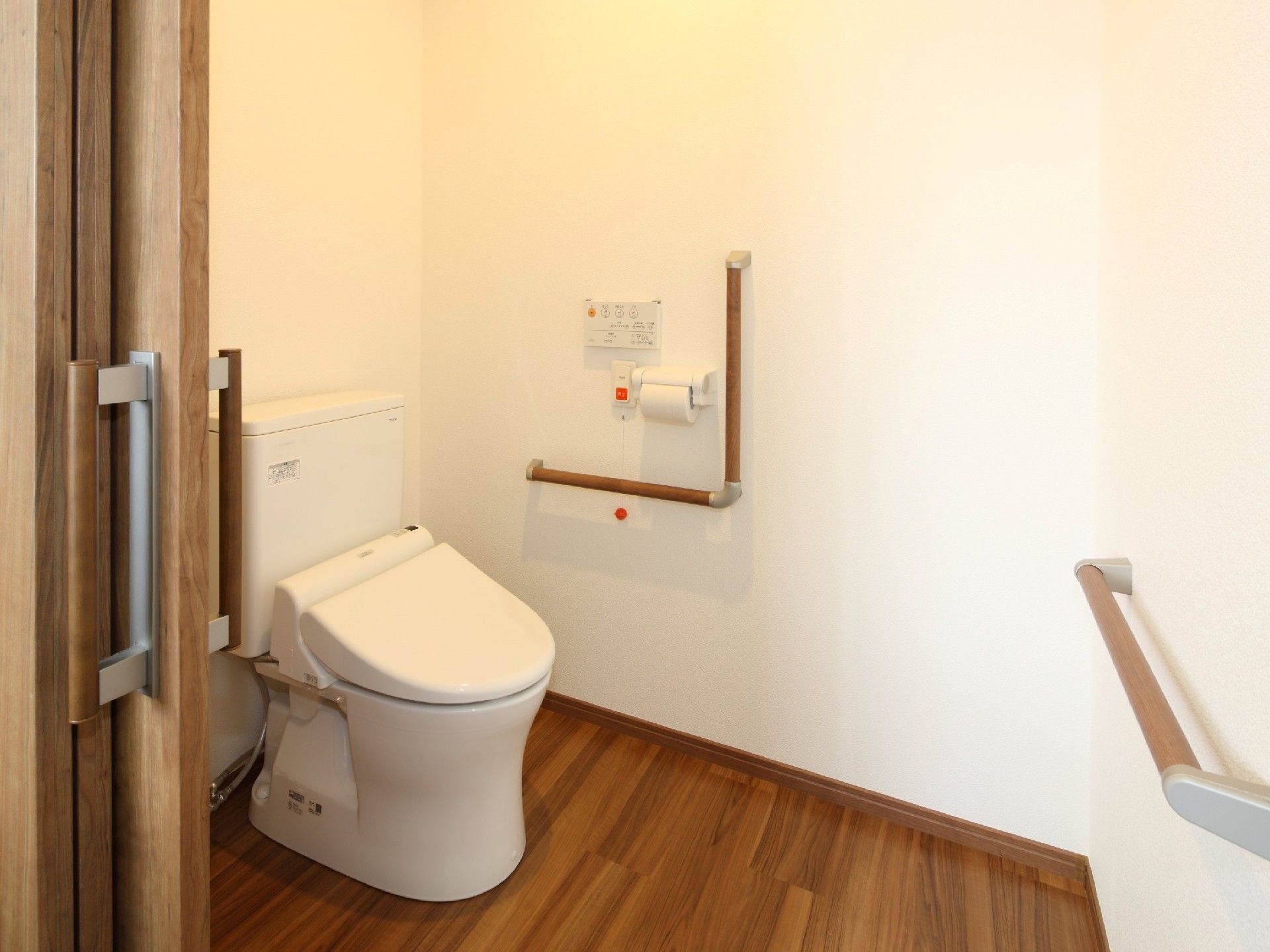 呼び出しボタンがついたトイレにはエル字型の手すりがあり、フローリングで介助スペースもある。
