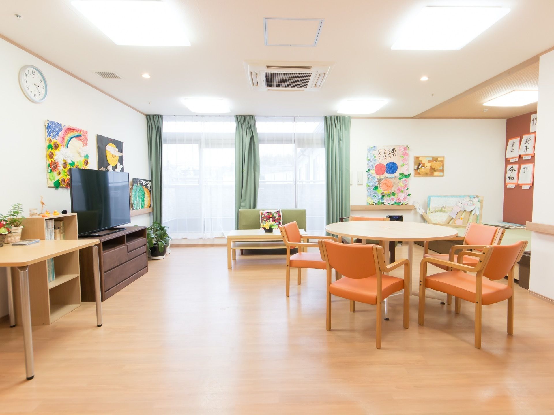 共有スペースは大きな窓があり明るい。テレビが設置されており、作品展示や観葉植物が置かれてアットホームな雰囲気。