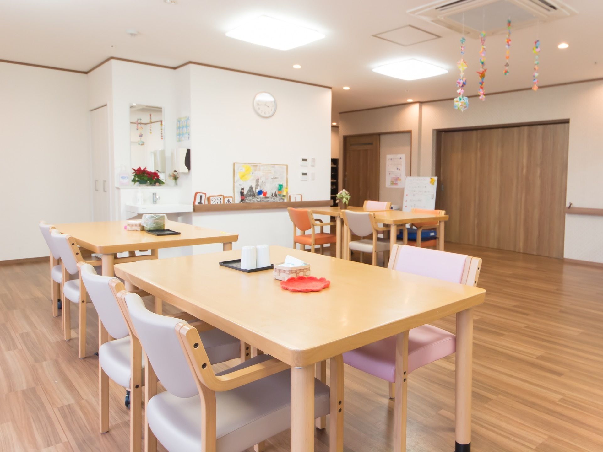 通路から続いている開放的な飲食スペース。デコレーションにより明るい雰囲気でテーブルの上にはコップとティッシュが置いてある。