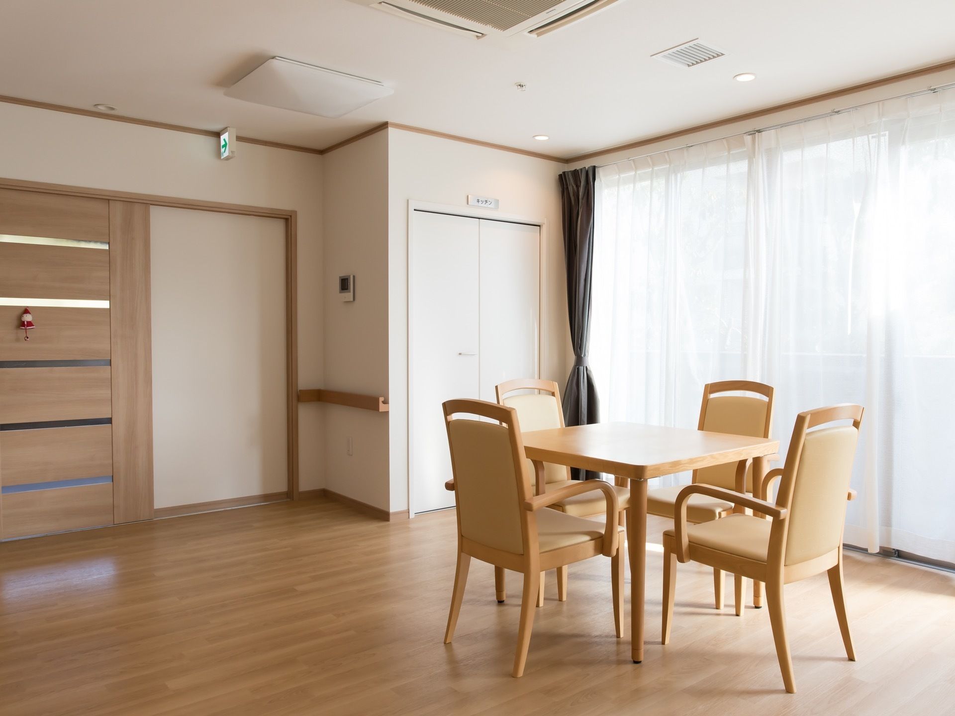窓にはカーテンが掛けられており、日の光が差し込んでいる。テーブルが置かれている。床はフローリングが施されている。
