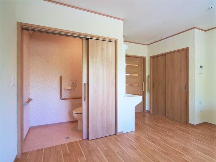 広いトイレにはエル字型の手すりが壁につき、洗面所や収納も設置されている。