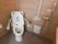 便座の両脇に手すりが設置されたトイレである。横壁にも手すり、ナースコールが取り付けてある。壁は、木目調となっている。