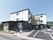 広い駐車場がある敷地内に、玄関にスロープが付いた３階建ての建物がある。