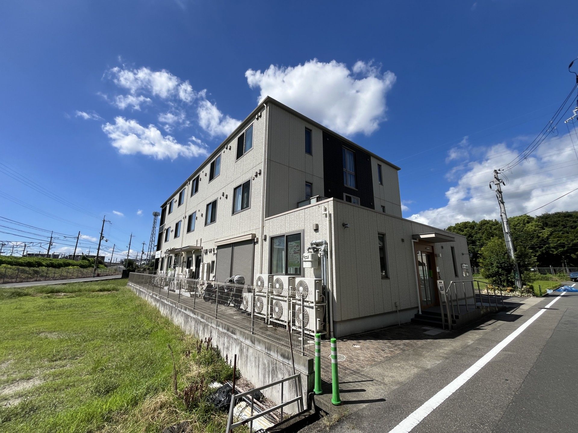 黒で所々アクセントが付いた白い建物は3階建て。広い駐車場も付き、明るい雰囲気。