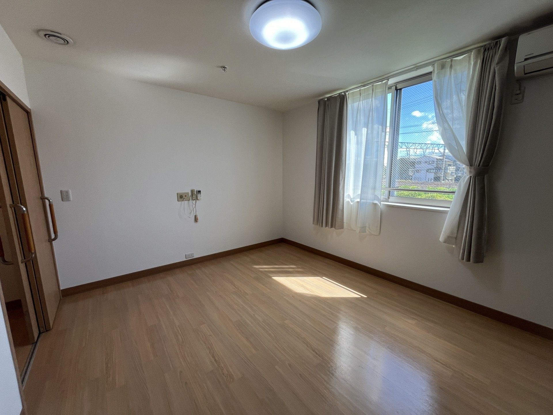 大小の窓が付き明るい居室。ベッドやサイドテーブルが置かれた部屋にはトイレと洗面所も付いている。