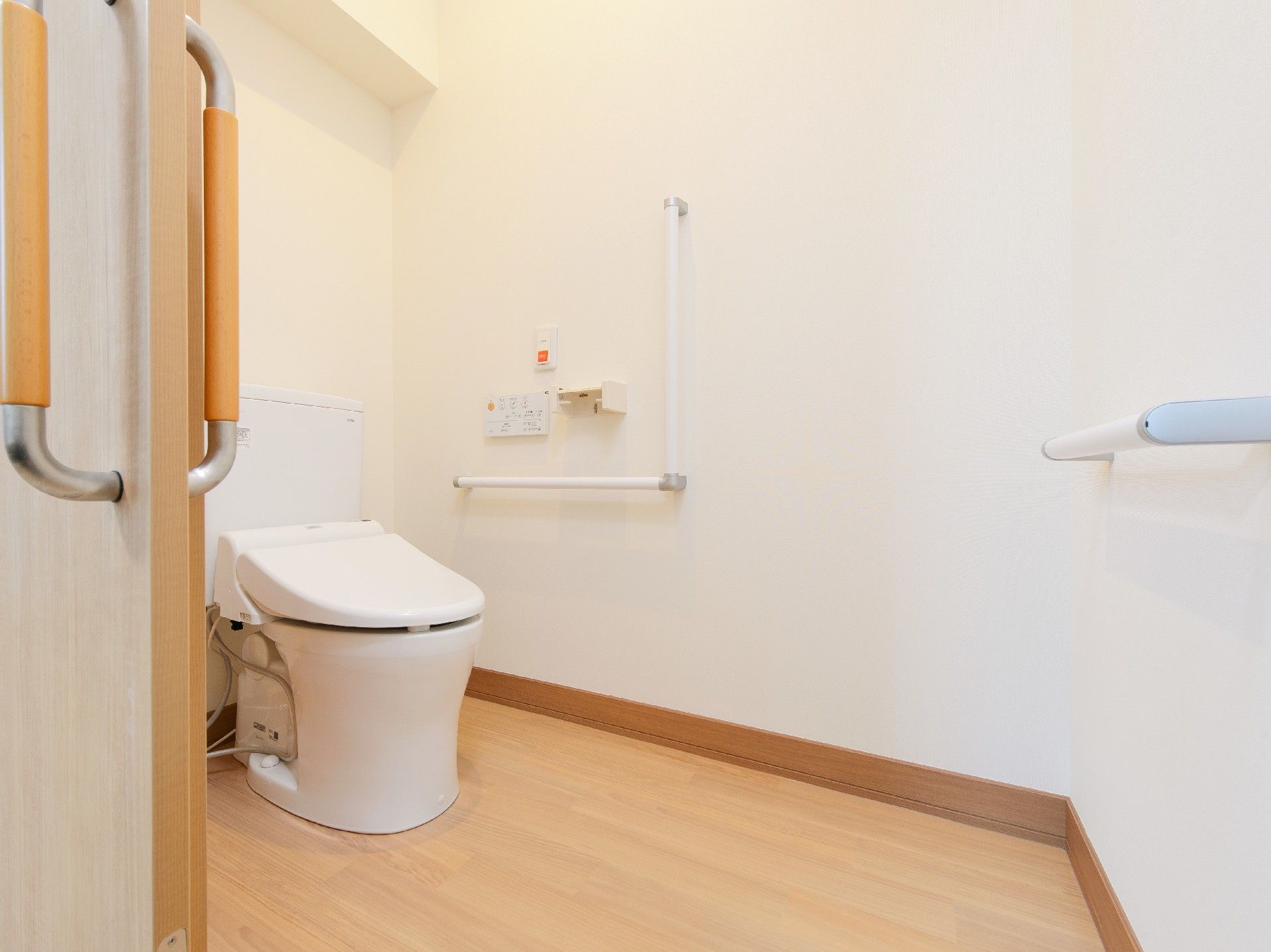 シンプルなトイレには手すりが付き、車いす対応の広さを確保。オレンジの呼び出しボタンもある。