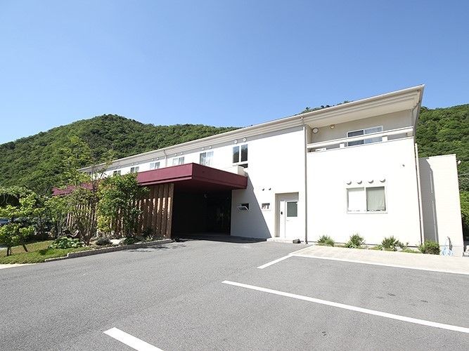 周囲を山に囲まれた広めの敷地内に建つサービス付き住宅おもいやりの外観