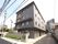 4階建ての建物はダークブラウンを基調としていて、門には住宅や併設事業所の名前が書かれたプレートが貼られている。