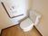 トイレの便座は温水洗浄式である。水洗ボタンは大きく押しやすい。壁の緊急呼び出しボタンは紐を引いても作動するタイプ。