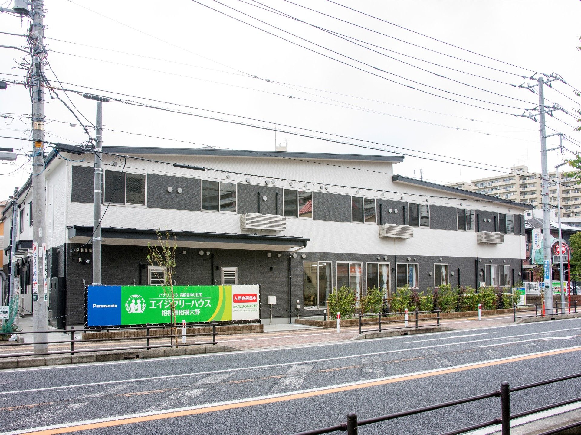 2階建ての建物。1階部分はダークグレー、2階部分は白で、道路に面している。