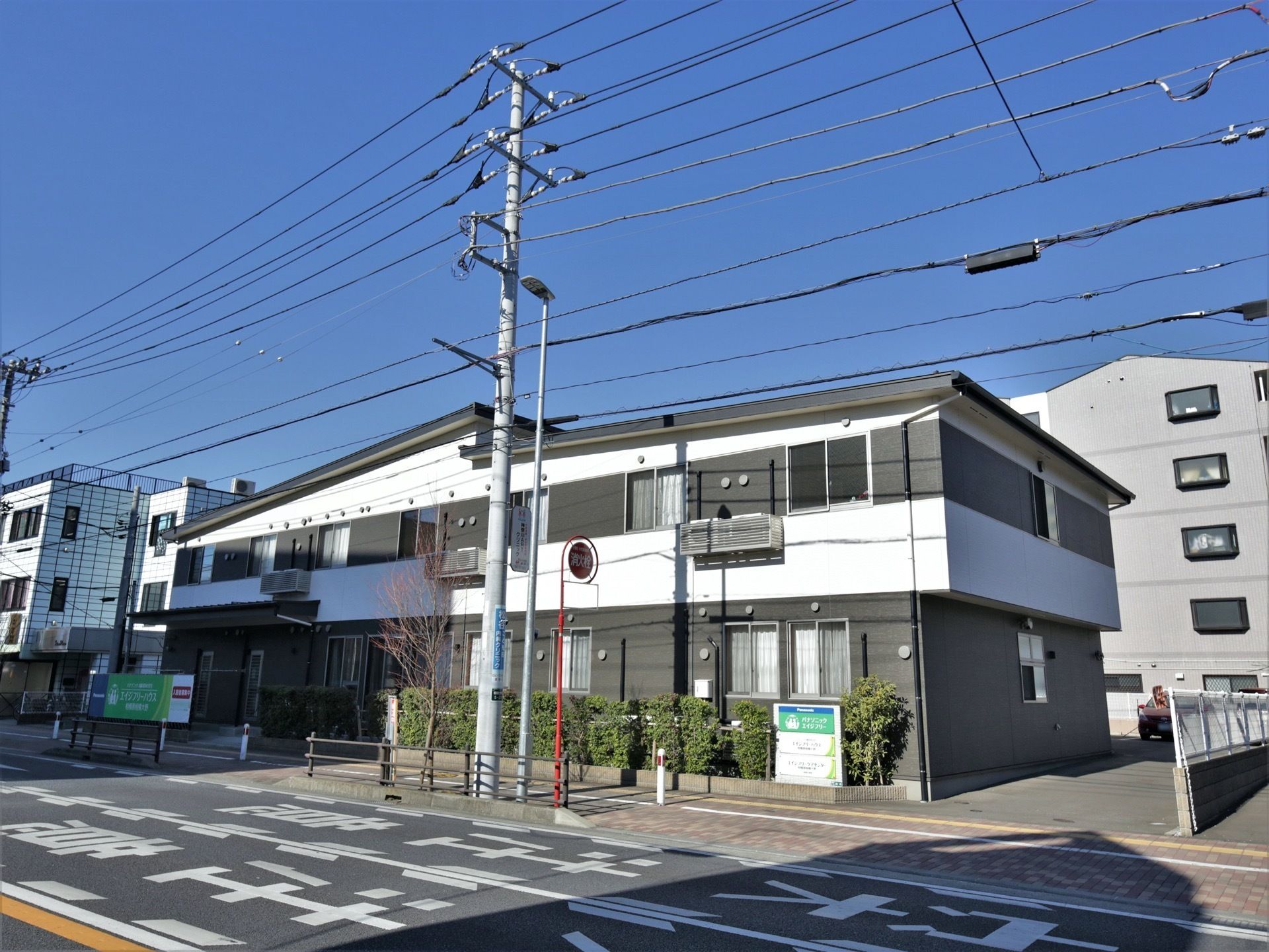 建物の右手に駐車場への入り口がある。植込みの看板が入り口の目印になる。駐車場は建物の裏手に設けられている。