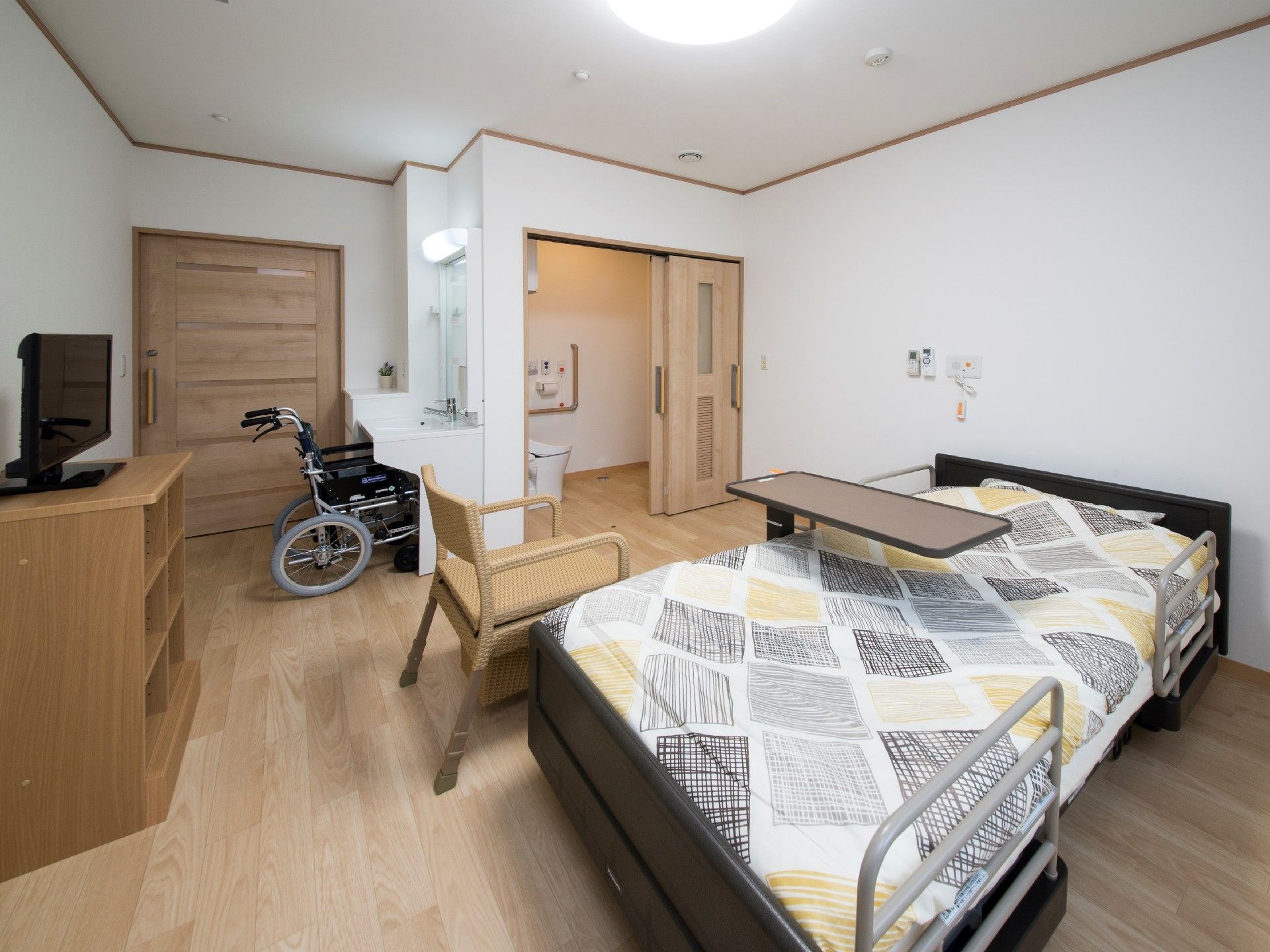 寝具がセットされたベッドが置かれたフローリングの部屋には、洗面所もある。