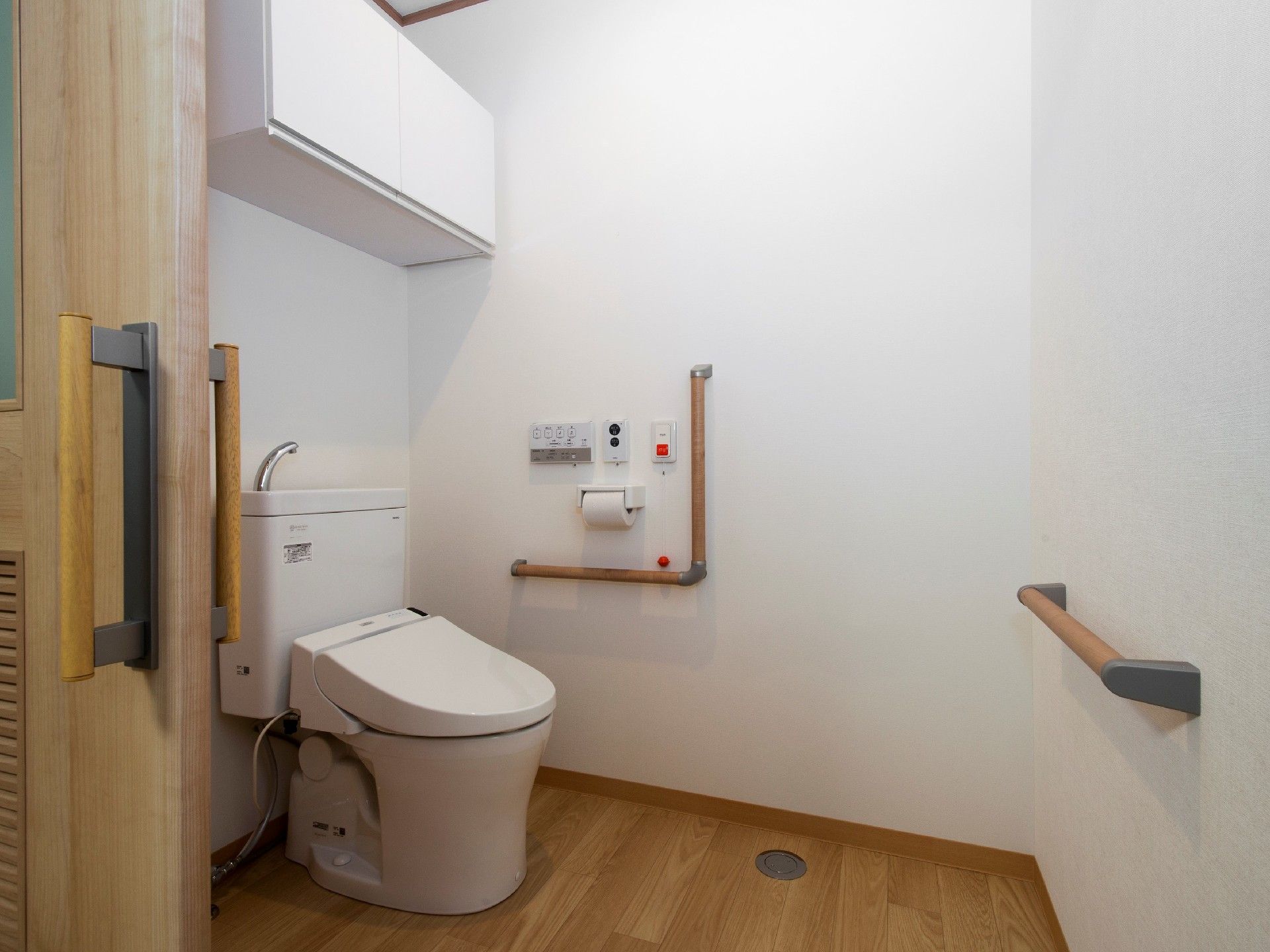 収納付きのトイレにはエル字型の手すりや呼び出しボタンが付いている。