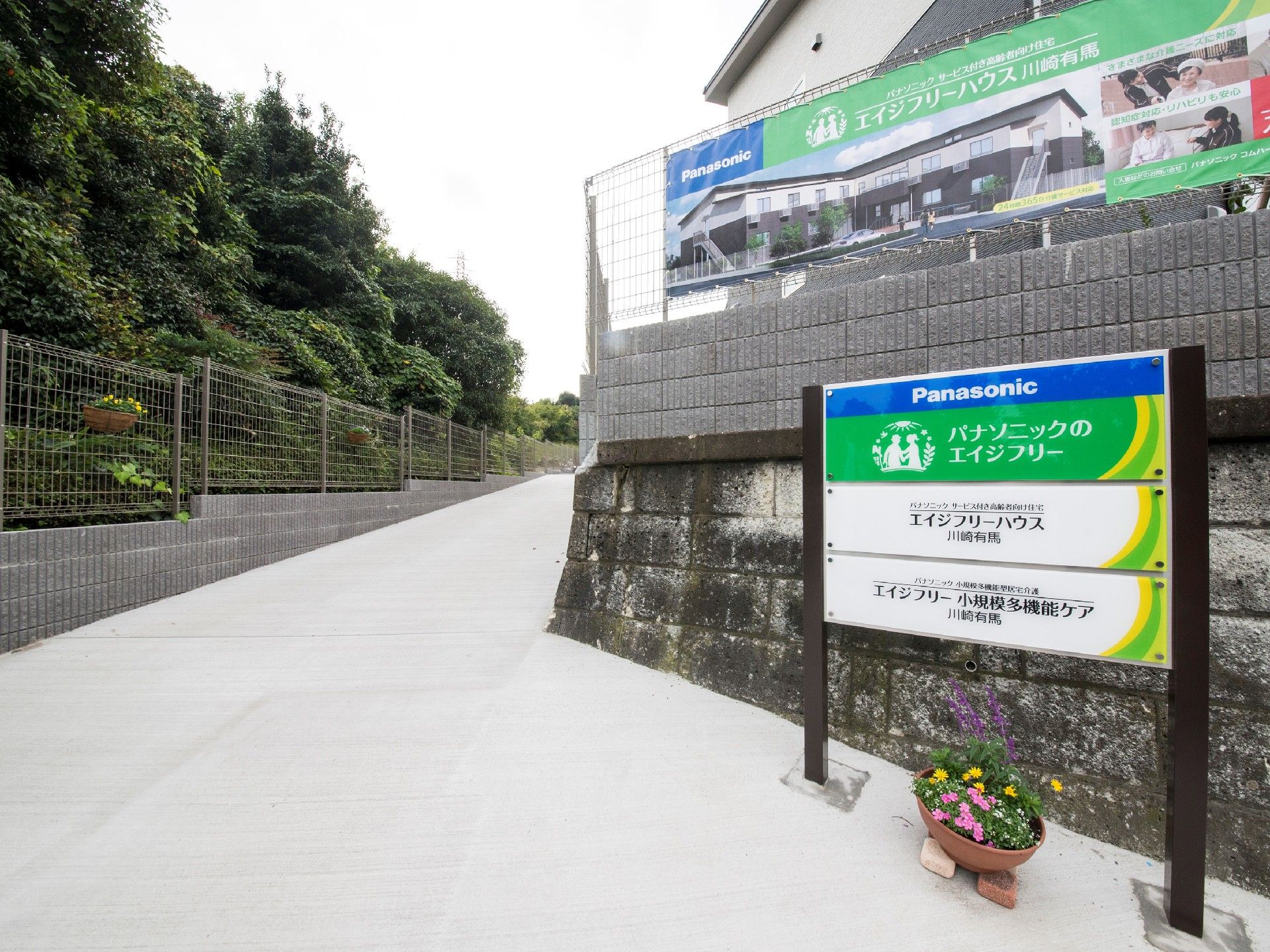 高台にある建物は緑に囲まれ、近くには案内看板も立っている。