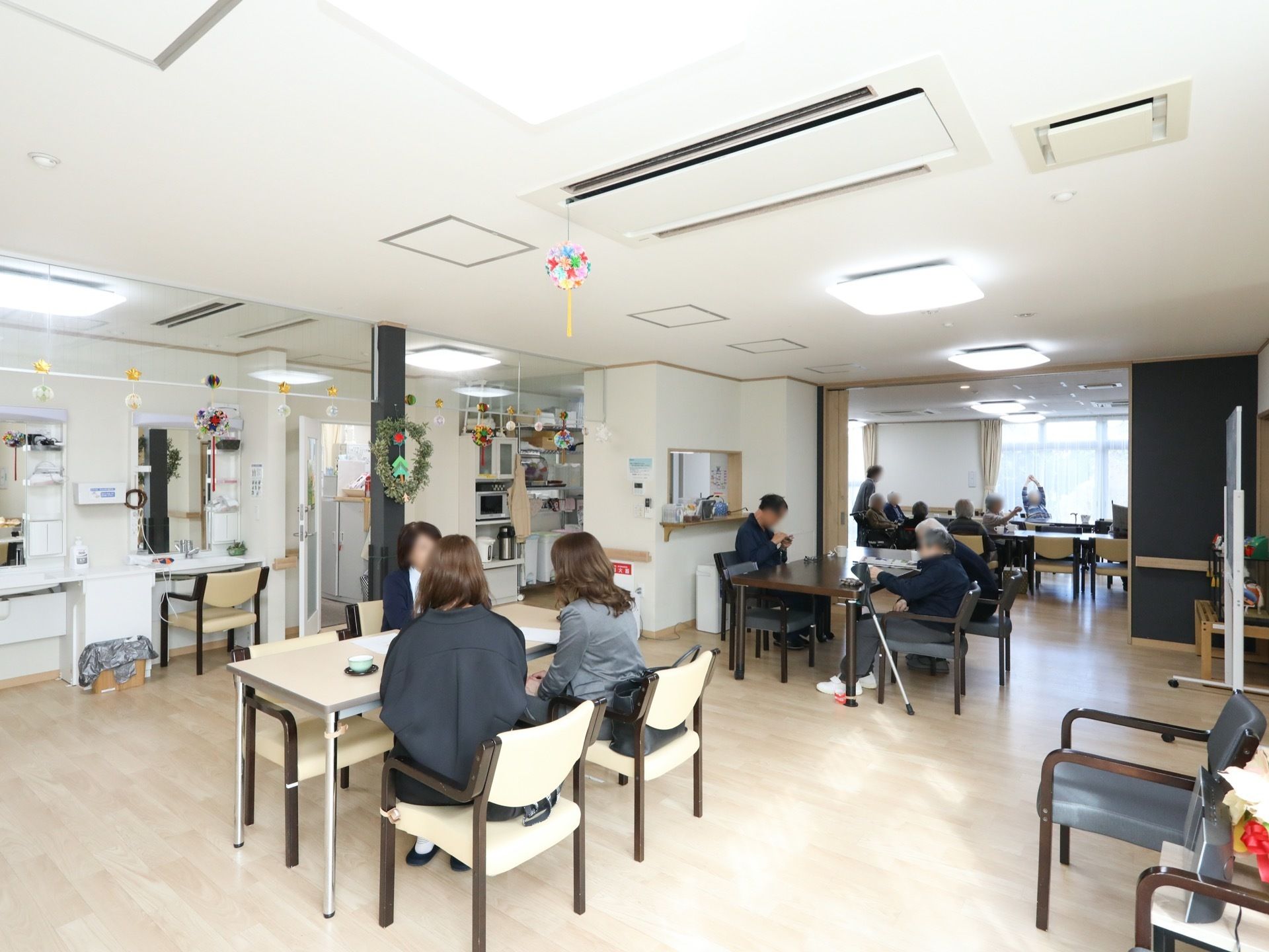 休憩スペースとつながっている食堂がある。手前のテーブルで打ち合わせが行われている。洗面台が並んで設置されている。