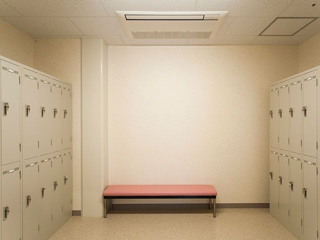 上下にロッカーが並べられたスペース。部屋の両サイドにロッカーが置かれ、赤いベンチもある。