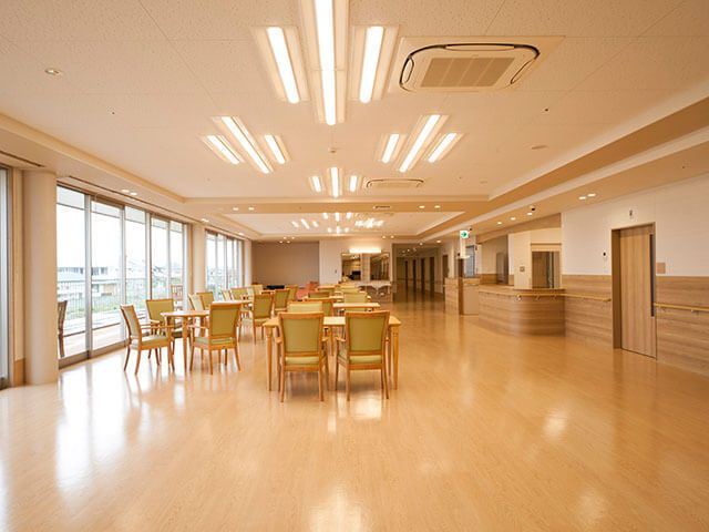 キッチン付きの食堂は大きな窓があり明るい雰囲気。少人数用のテーブルセットが多数置かれている。