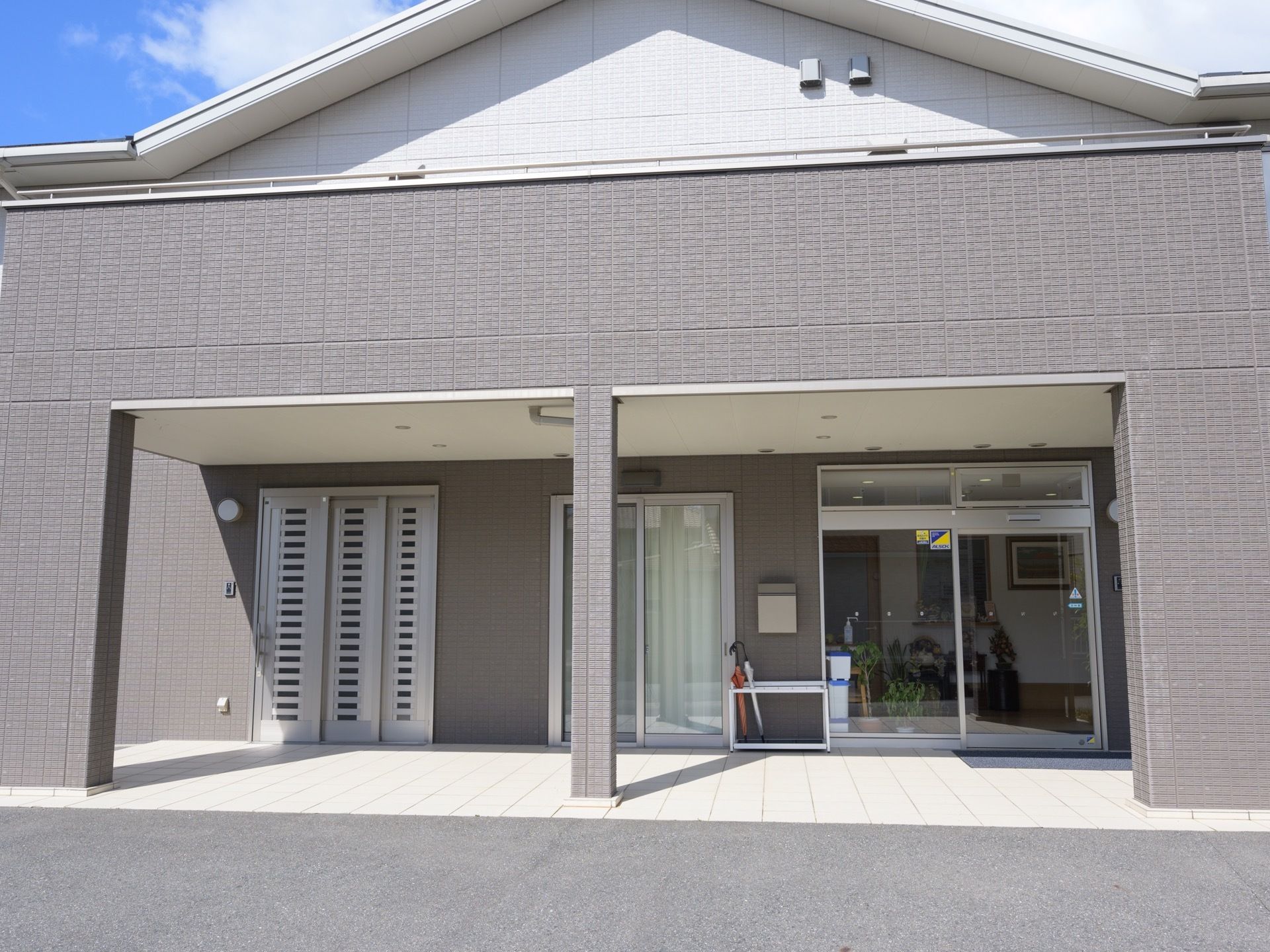 明るいグレー系の施設建物正面には、入口が3箇所設けられている。2階部分のベランダがせり出し、屋根部のあるポーチ仕様となっている。