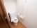 引き戸で仕切られたトイレがある。壁にはＬ字型に手すりが設置されているほか、緊急用の通報装置が取り付けられている。