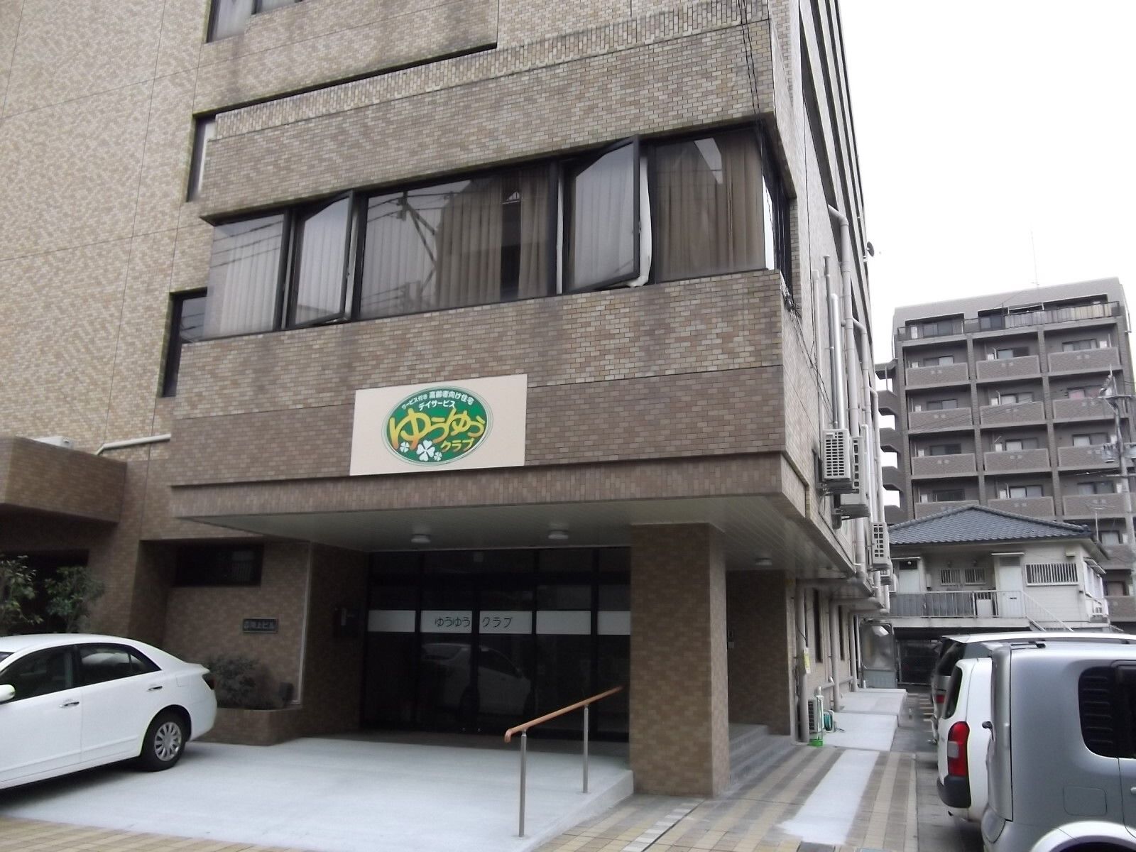 高齢女性たちと白衣を着た女性スタッフがベージュのソファを囲んで話している。