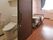 引き戸が付いたトイレが居室にあり、奥のフローリングのスペースには介護ベッドやタンスが置かれている。