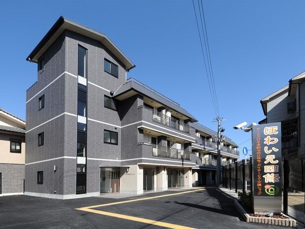 広い敷地内にはグレーの3階建ての建物があり、敷地への出入り口には大きな看板もある。