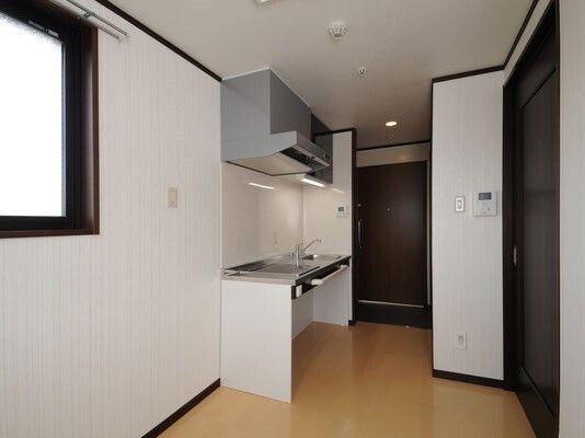 足元にスペースがあるキッチンが付いた部屋。フローリングフロアで玄関ドアも大きい。