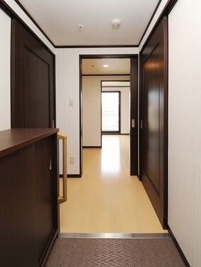 段差のない玄関医は靴箱が設置され、フローリングのフロアが奥へ続いていて、広い居室スペースが見える。
