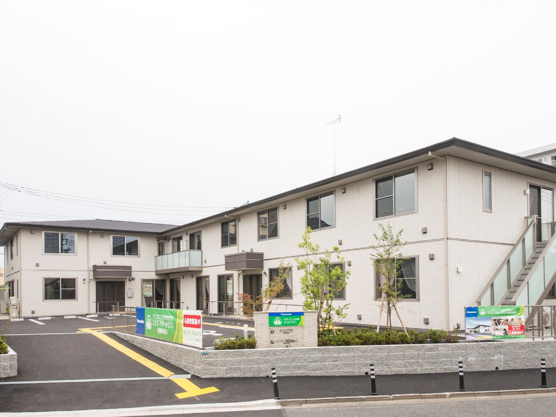 エル字型の建物は2階建てで白を基調としている。屋外階段もある。