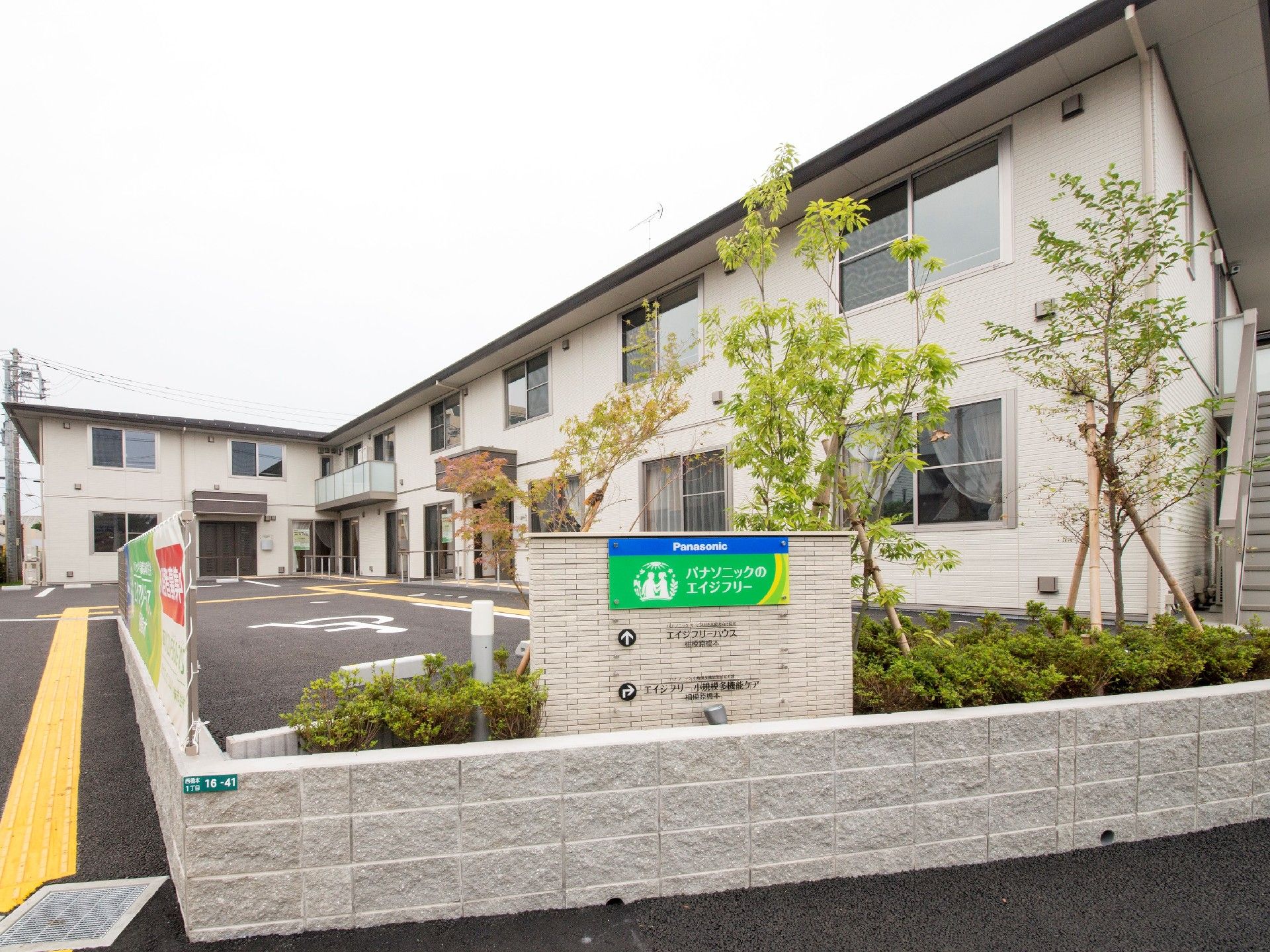 広い駐車場があり、車寄せが付いた建物の前には青、緑などが使われた看板も立っている。