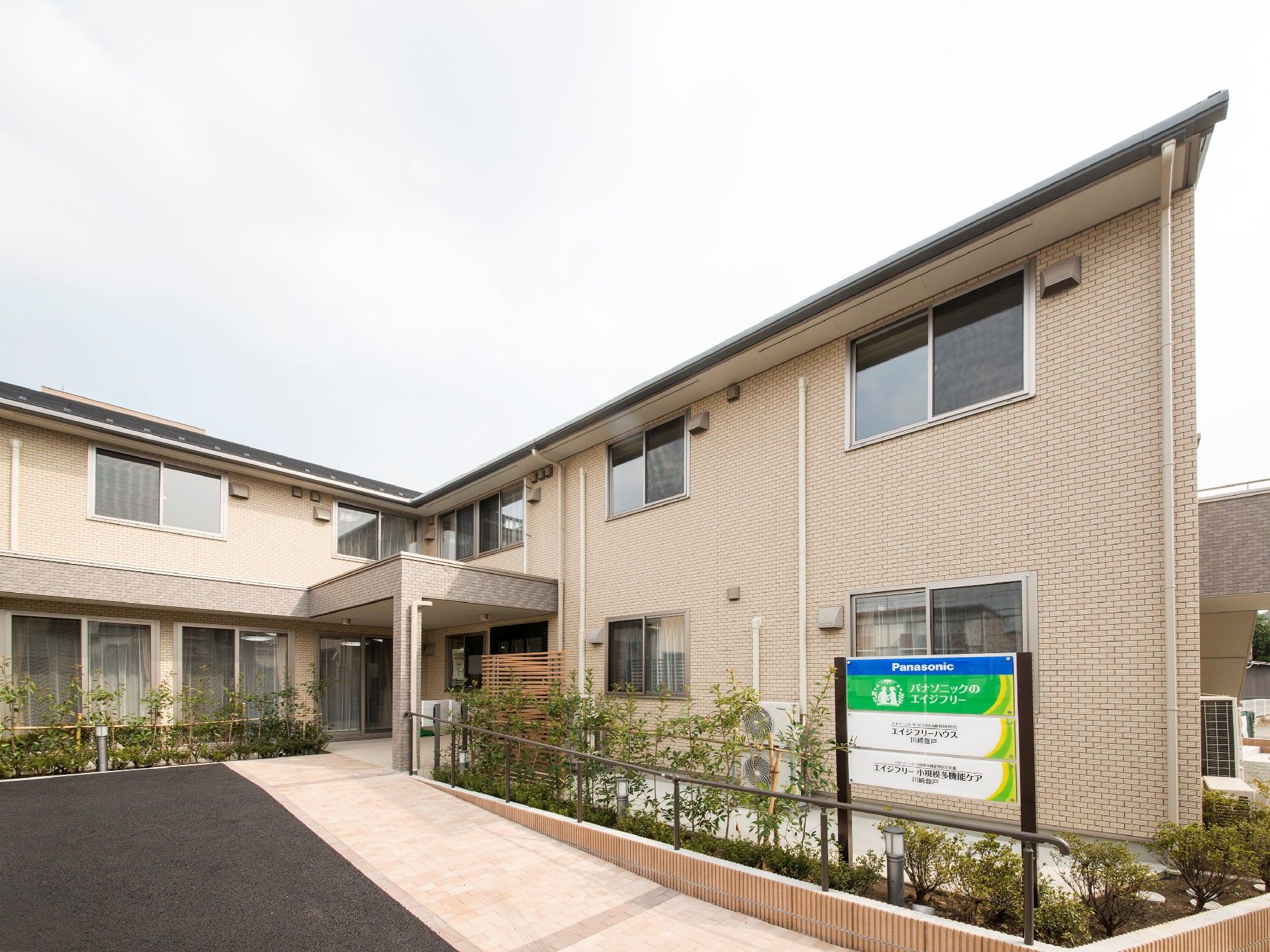 玄関からはなだらかなスロープがつき、2階建ての建物の前には看板が立っている。