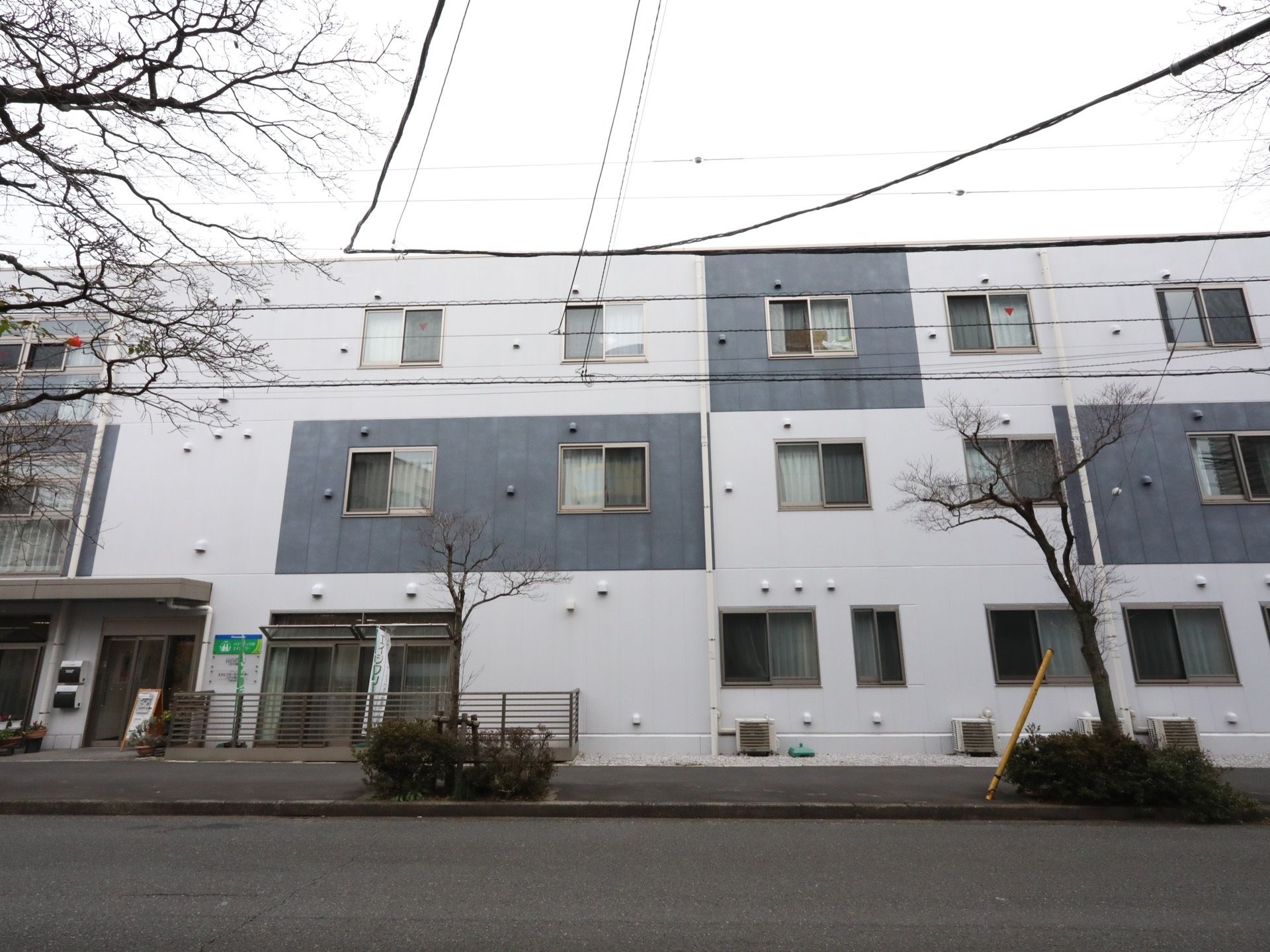 施設は道路に沿って、横長にゆったりと建てられている。グレーと白のツートンカラーが特徴的で、おしゃれなデザイナーズマンションのような外観。