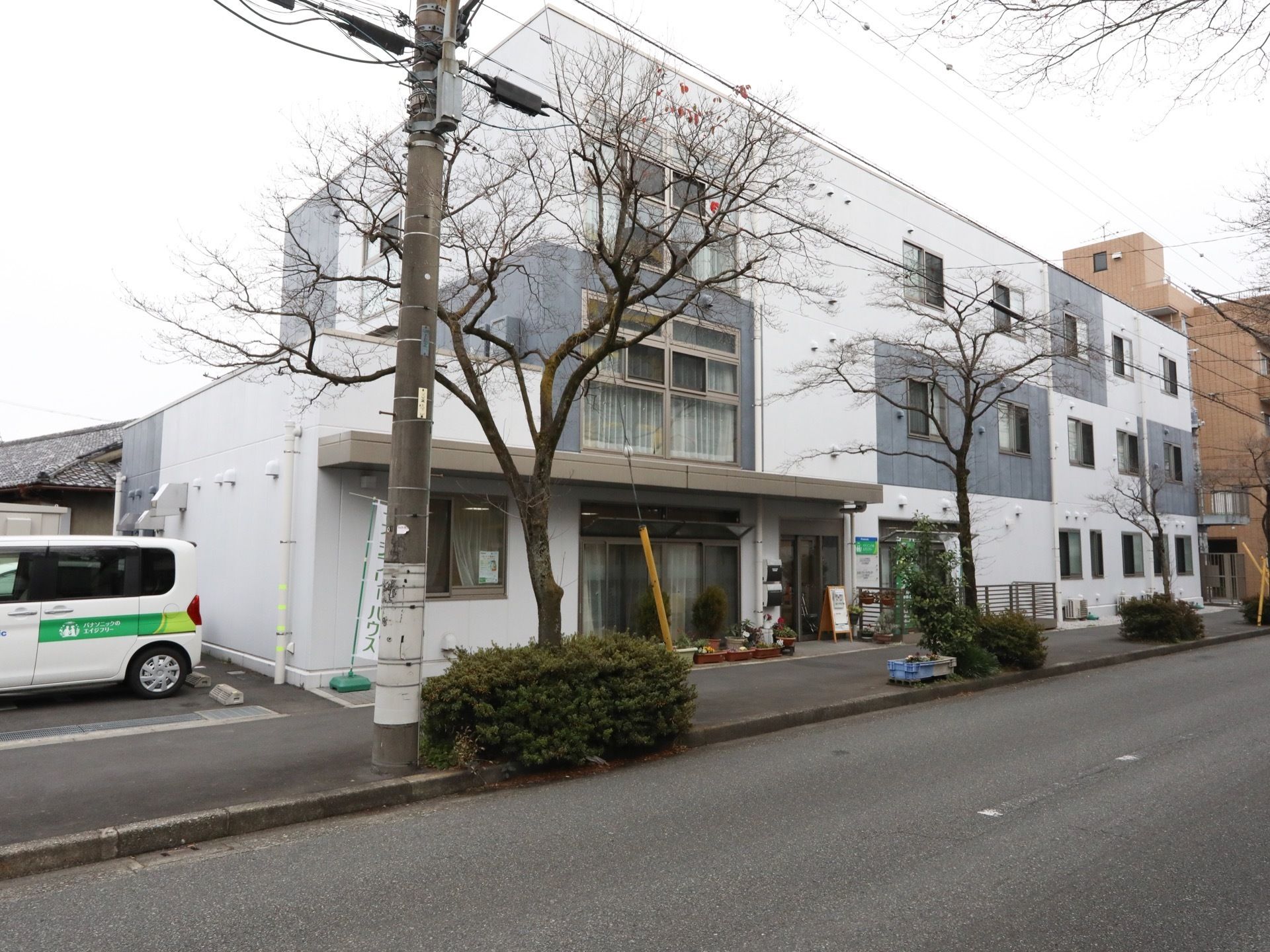 敷地内には駐車スペースが設置され、送迎車が停められている。建物には窓が多数設置されて、自然光を採光できるようなデザインにしている。