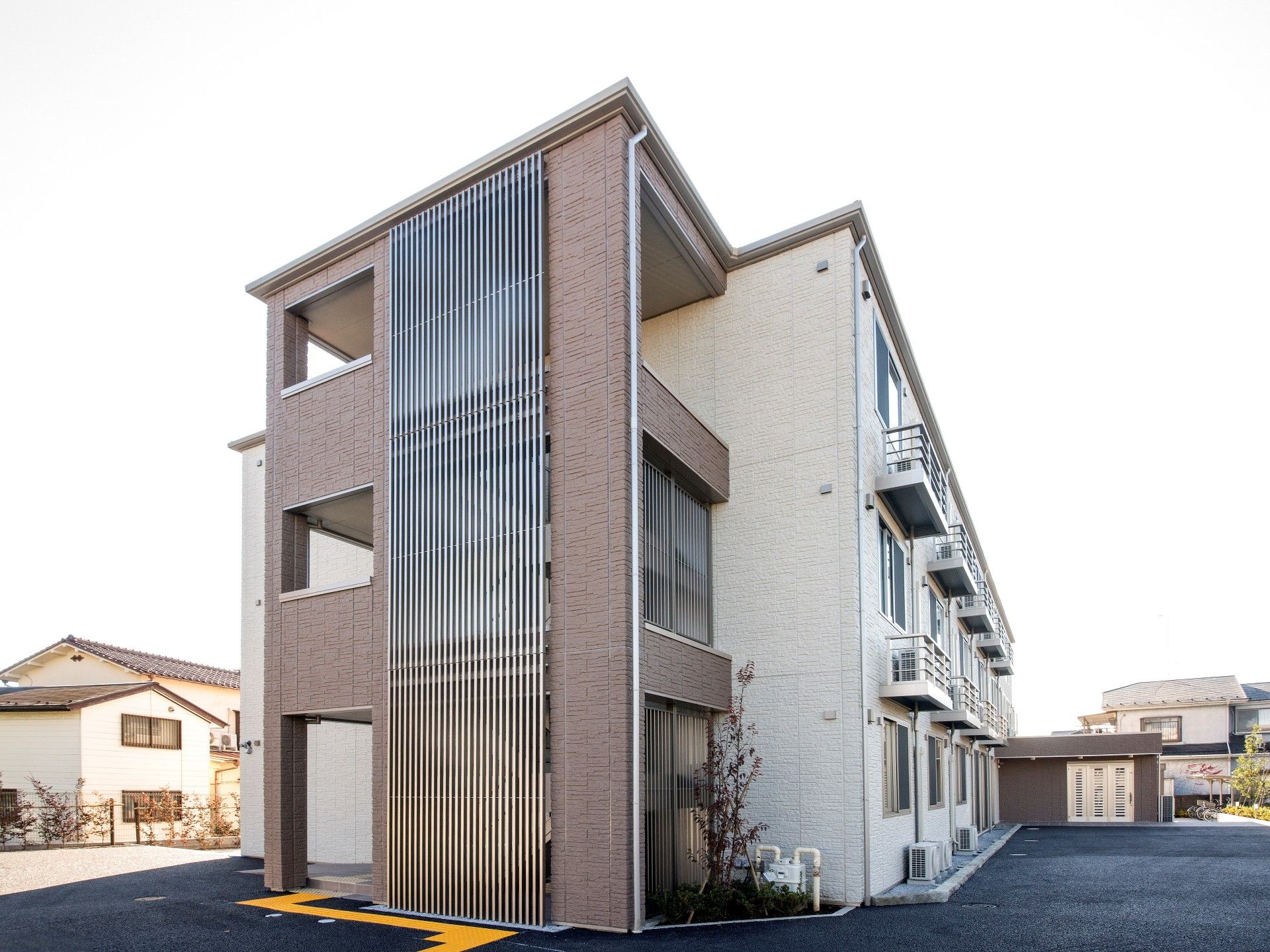 ブラウン系でまとめられたどっしりとした建物。玄関には屋根が付き、屋外階段もある。
