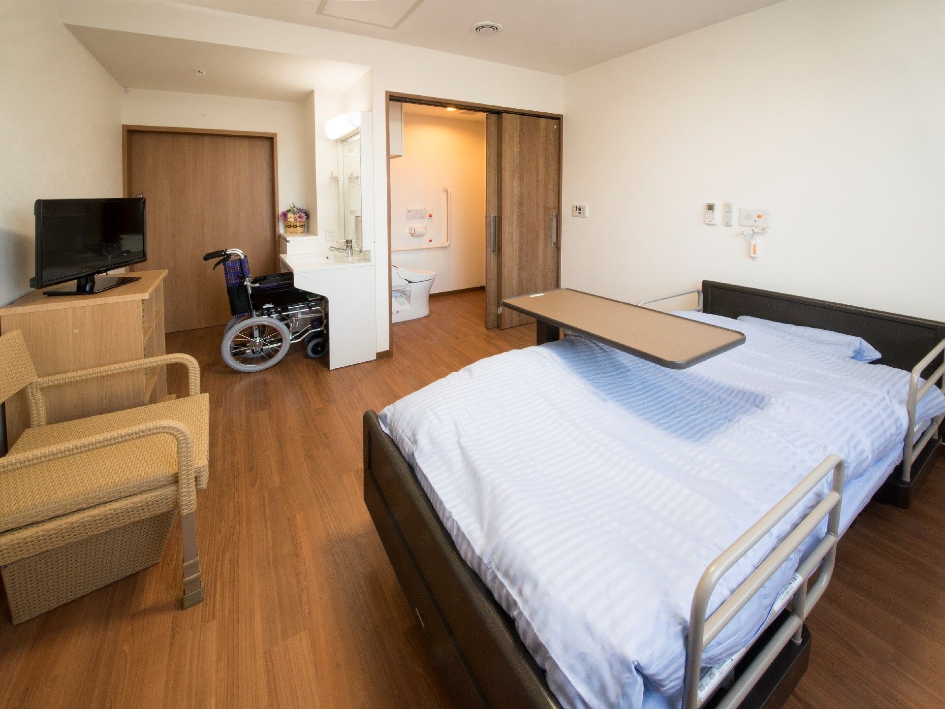 介護ベッドなどの家具が設置されたフローリングの居室には、トイレや洗面所も付いている。