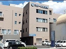 駐車場が付いた４階建ての建物の周りには緑があり、外壁にはホーム名もある。
