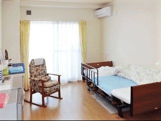 フローリングで、ベッドやエアコン、いすなどの家具が置かれた部屋には大きな窓もある。